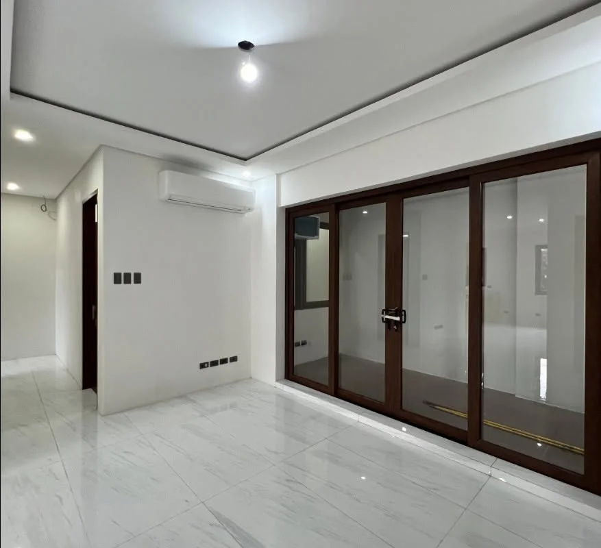 Living area with marble-look tile flooring, a wall-mounted air conditioner, and a wide wood-framed sliding glass door system leading to an outdoor terrace